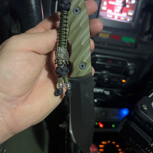 ELE Survival knife in hand with green paracord lanyard