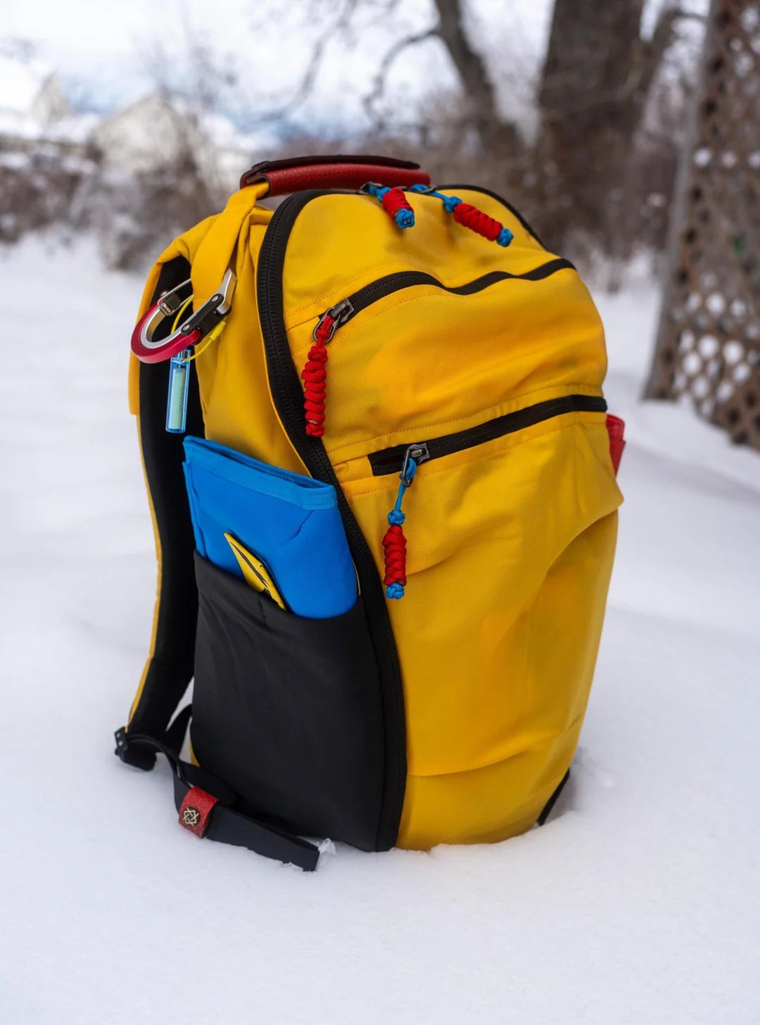 ELE Survival zipper pulls on yellow backpack in snow